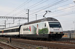 Re 460 035-9, mit einer Helvetia Werbung , durchfährt den Bahnhof Muttenz.