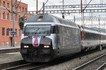 Re 460 028-4, mit einer SBB Personal Werbung, durchfährt den Bahnhof Muttenz.