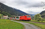 Ein Matterhorn-Gotthardbahn-Zug mit dem Glacier Express erklimmt oberhalb Disentis den ersten Zahnstangenabschnitt unterwegs zum Oberalppass, mit Blick auf das Kloster Disentis.