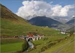 Warten auf HG 4/4 704 im Urserental. In der Zwischenzeit darf auch noch HGe 4/4 II 104 mit dem GEX im Schlepptau passieren, während ein Sonnenstrahl die Szene erhellt.  Im Hintergrund Andermatt und der Weg zum Oberalppass. Hospental, September 2018.