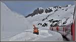 R923 mit HGe 4/4 107 überholt kurz vor der Oberalppasshöhe eine Schneefräse des Bündner Strassenbauamtes.