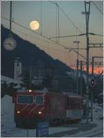 HGe 4/4 102 rangiert ihren MGB Zug im Bahnhof Disentis und wird erleuchtet von einem riesigen Vollmond.