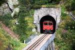 Die Dampfbahn Furkabergstrecke führt jeweils einige Züge für Wanderer und Radfahrer von Realp nach Oberwald und zurück mit einer Diesellok. Hier erscheint am 06.09.2024 die Lok im unteren Portal des Kreiskehrtunnels bei Gletsch. Es gibt nur wenige grosse Diesellokomotiven mit Zahnradantrieb. Diese Maschine ist somit etwas aussergewöhnliches.