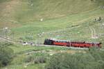 Zum Jubil�um 100 Jahre FO fuhr morgens ein Extrazug nach Realp um die G�ste abzuholen. Hier erreicht der Zug den Bahn�bergang im Landwirtschaftsgebiet zwischen Realp und Hospental am 04.07.2026.