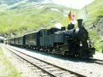 DFB Dampfzug in Furka-Station (2163m .M.)auf der Rckfahrt von Gletsch nach Realp.Hinter der Lok die Fahnen vom Kanton URI,Kanton Wallis und die DFB Fahne.14.07.05