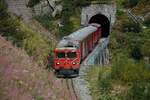 Die HGm 4/4 62 der Matterhorn-Gotthardbahn (ex FO) zieht am 06.09.2024 einen Zug der Furkadampfbahn aus dem Kehrtunnel bei Gletsch talwärts.