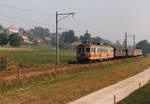 CHEMINS DE FER FRIBOURGEOIS GRUYERE - FRIBOURG - MORAT/GFM.
BAHNIDYLLE IM FREIBURGERLAND.
ABDe 4/4 164 mit vier Personenwagen verschiedener Generationen als Zug 60 von Murten nach Fribourg unterwegs vor der ländlichen Kulisse der Gemeinde Cressier am 5. Oktober 1986.
Die beiden grünen schweren Personenwagen B 343 und B 341 hat die GFM von der SBB übernommen. Stationiert waren sie während mehreren Jahren auf dem damaligen Endbahnhof Ins. Zum Einsatz gelangten sie als eiserne Reserve und Verstärkungswagen bei Grossanlässen wie dem alljährlichen Murtenlauf.
Foto: Walter Ruetsch   