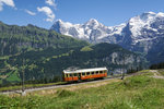 Panoramablick auf Eiger, Mönch und Jungfrau, während im Vordergrund der CFe 2/4 11 seinem Ziel Grütschalp entgegenfährt (14.08.2016).