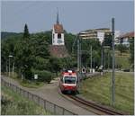 Ein Waldenburger Bahn (WB) Regionalzug mit dem schiebenden BDe 4/4 16 auf der Fahrt nach Liestal vor dem Hintergrund der Kirche von Oberdorf.