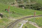 Die Andreaskreuze sind bei der BRB neu ab Saison 2014. Sie mussten aufgrund von Auflagen praktisch bei allen Bahnübergängen entlang der 7.6 km langen Strecke erstellt werden, so auch hier beim Kühmattdamm / Überquerung Wanderweg. Diese Signale kosten um CHF 50'000, die anderswo wieder reingeholt werden müssen. Foto vom 09. Juni 2014, 15:53