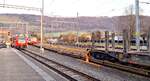 CJ Bf Glovelier__Während der Linienzug von La Chaux-de-Fonds mit ABe 4/12 671 einfährt wird ein N-Spur-Rungenwagen zum Holztransport auf die M-Spur Rollschemel der CJ gedrückt. Als 'Zuglok' für den Rollschemel-Zug nach Saignelégier dient üblicherweise ein älterer Personen-Tw so wie hier Be 4/4 617 (ex Frauenfeld-Wiel-Bahn).__27-02-2026