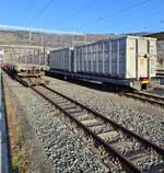CJ Bf Glovelier__ Hochbetrieb  auf den M-Spurgleisen. Links ein aufgebockter Rungenwagen, rechts ein Zug mit Müll-Containern.__27-02-2026