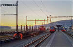 CJ Bf Glovelier__Der Rangierbetrieb im Bf Glovelier startet am frühen Morgen. Das laute Klacken beim Öffnen der Gleissperre im SBB Bahnhofsgleis gegen 6 Uhr bildet sozusagen den Startschuß. Im Bild drückt die CJ Rangierlok einen leeeren N-Spur Rungenwagen auf einen M-Spur Rollwagen der CJ. Daneben ABe 4/12 671 und ein Altbau-Tw.__27-02-2026