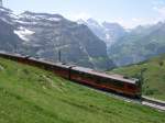 Am 28.06.2005 fhrt dieser Zug der Jungfraubahn zwischen Eigergletscher und Kleiner Scheidegg. In Krze wird er seine Ladung Japaner an der Kleinen Scheidegg ausladen. Wir blicken hier in das Lauterbrunnental. Am gegenberliegenden Berghang liegt Mrren.