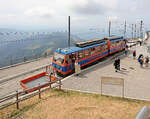 Ferrovia Monte Generoso: Triebzug 14 auf dem Generoso-Gipfel. Die Wagenf�hrerin r�umt gerade das Uebergangsblech weg, �ber welches eine Rollstuhlfahrerin ausgestiegen ist. 23.Juli 2026  