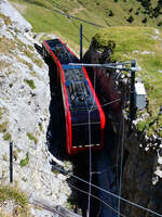 Der Doppeltriebwagen im schattigen Einschnitt, kur vor der Einfahrt in den Tunnel. Das Foto wurde vom Wanderweg aus aufgenommen. Pilatus Kulm, 19.8.2026