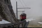 Bhe 1/2 30 der Pilatusbahn hebt sich deutlich vor dem Hintergrund der Wolke ab als er am 10. Mai 2015 vormittags etwas unterhalb der Bergstation um den Esel gekrochen kommt.