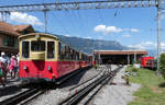 Die beiden Z�ge von der Schynige Platte sind soeben angekommen, die Fahrg�ste steigen aus. Vom �bergang auf den Bahnsteig ist ein Blick aus der Ferne Richtung Depot m�glich. Wilderswil, 22.7.2026