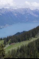 Hoch über dem Brienzersee fährt ein Zug der Schynige Platte Bahn mit Lok 62 am 31. Mai 2015 bergwärts. Der Zug befindet sich kurz nach der Station Breitlauenen. Im Hintergrund ist das Brienzer Rothorn zu sehen.