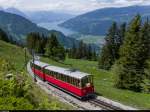 He 2/2 61 der Schynige Platte Bahn schiebt am 31. Mai 2015 kurz vor der Zwischenstation Breitlauenen einen Zug bergwärts. Im Hintergrund der Thunersee mit dem Niesen (links) und dem Niederhorn (rechts).