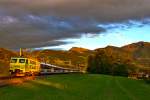 Passend zum Abendrot(wie Bonbonfarben aber nicht zu vermeiden in den Alpen) bei einer föhnigen Aufhellung schiebt die giftgelb neulackierte SOB Lokomotive RE 456 018  Akademie St.Gallen  am