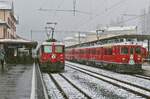 Während die Ge 4/4 II 611 noch auf die Abfahrt warten muss, verlassen die ABe 4/4 56 und 54 mit einem Zug von Tirano nach St. Moritz während eines heftigen Schneeschauers am 30.03.2022 den Bahnhof Pontresina