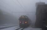 Nebelaufnahme des aus Tirano in Alp Grüm einfahrenden Zug mit dem ABe 4/4 III 51 an der Spitze am 30.03.2022 