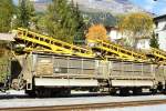 RhB - Fau 8755 am 03.10.1990 in Davos Platz - Altschotter-Selbstentladwagen mit Kippvorrichtung, 2 Kippmulden und Schienenzangen fr Altschotter mit Frderband 4-achsig mit 1 offenen Plattform -