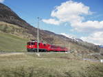 Ein Regionalzug der Rhätischen Bahn mit Lok 629 auf freier Strecke in idyllischer Landschaft.