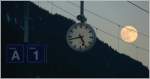 Die Hilfikeruhr gehrt zu einem Schweizer Bahnhof wie der Mond zur Erde. Fotografiert in Disentis/Mustr in der Surselva, wo romanisch gesprochen wird. (siehe Tafelanschriften) (10.01.2009)