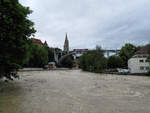 Hochwasser in Bern - Blick von der Aare auf die Kirchenfeldbrücke, auf der ein Siemens-Combino Tram (Serie 753-759, nur fünfteilig) vorüberfährt.