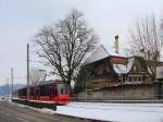 Berner Strassenbahn unter uralten Bäumen ehrwürdiger Landsitze: Bernmobil Combino-Wagen 765 auf der Ueberlandbahn des Regionalverkehrs Bern-Solothurn. Vor den zum Schloss Muri gehörenden Gebäuden, 21.Januar 2016. 