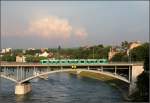 . Im Hintergrund eine Gewitterwolke - Ein Combino-Tram auf der Basler Wettsteinbrcke im Abendsonnenlicht. Hinter der Brcke kmpft ein Schiff gegen die Strmung des Rheins an. 18.06.2013 (Matthias)