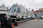 Nach dem der Lastwagen in Position gefahren ist, wird am Ende des Lastwagens eine Rampe moniert, die genau auf dem Gleis endet. Das Tram wird vorne mit einer Seilwinde gesichert und ganz langsam rollt das Tram vom Lastwagen ins Depot. Die Aufnahme stammt vom 04.09.2014.