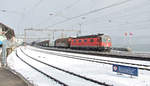 Die Re 620 064-6 ist mit einem Ferngüterzug RBL-Buchs SG bei Schneefall und Sonnenschein entlang des Zürichsees unterwegs.