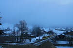 Vor Sonnenaufgang: Ganz knapp lassen sich die Anhöhen oben rechts durch den zähen Nebel erraten, während ein Zug der Wengernalpbahn von Lauterbrunnen aus die Steigeung nach Wengen in