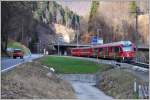 RE1045 mit ABe 8/12 3507 überholt bei der Einfahrt zur Ausweichstelle Fuchsenwinkel ein landwirtschaftliches Fahrzeug, ebenfalls in RhB-rot.