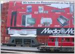 Wie eine Spielzeugeisenbahn wirkt die RhB in Chur vor dem Neubau  Alex , der mit einer riesigen Werbefolie verpackt wurde.