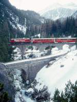 RhB Schnellzug 540 von St.Moritz nach Chur am 03.03.1998 auf Albula I-Viadukt zwischen Preda und Muot mit E-Lok Ge 4/4III 641 - 2x A - 3x B - D. Hinweis: Lok mit Werbung: Bernina-Express, gescanntes Dia
