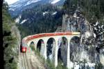 RhB Schnellzug 551 von Chur nach St.Moritz am 14.03.1999 auf Landwasser-Viadukt bei Filisur mit E-Lok Ge 4/4 III 647 - D 4222 - B 2368 - B 2374 - B 2491 - A 1242 - A 1275 - B 2465 - B 2327- Hinweis: Lok mit Werbung: CAPITO, gescanntes Dia

