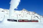 RhB - Dampfschneeschleuderextrazug 9462.2 fr Graubnden Tours von Alp Grm nach Ospizio Bernina am 28.02.1998 am Lago Bianco mit Dampfschneeschleuder X d rot 9213 - Triebwagen ABe 4/4 I 30 + ABe 4/4 I 30. Hinweis: Dampfschneeschleuder beim Schleudern, Triebwagen verkehren heute in gelber Lackierung, gescanntes Dia.
