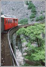 Ein ABe 4/4 mit zweiachsigem, grnen Gepckwagen auf Talfahrt ber das Kreisviadukt von Brusio. (Archiv 06/83)