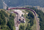 Kurz nach 14 Uhr, zwei Bahnhöfe auf einen Blick. In Alp Grüm (2091 müM) wartet der Bernina-Express St. Moritz - Tirano auf die Einfahrt des Gegenzuges. Links im Hintergrund ist die Station Cavaglia sichtbar. Das Foto wurde vom Aussichtspunkt Sassal Masone aus gemacht. Alp Grüm, 7.8.2025