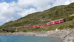 Roter Zug mit gelben Aussichtswagen: Regio von St. Moritz nach Tirano in der Nähe der Station Ospizio Bernina (2253 müM) in Richtung Süden. Ospizio Bernina, 7.8.2025