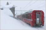 BerninaExpress 953 vor dem fast vollstndig eingeschneiten Bahnhof Ospizio Bernina.