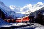 RhB BERNINA-EXPRESS Winter 425 von St.Moritz nach Tirano am 31.03.1996 in der Montebello-Kurve mit Triebwagen ABe 4/4III 51 - B - BD - AB - B - B. Hinweis: Blick zum genau 9 km entfernten Piz Bernina (4020m) mit Biancograt (Berg ber Triebwagen) , links davon Bellavista. Im Winter ist durch den tiefen Sonnenstand lange Schatten an der Fottostelle. Nur 2 bis 3 Zge sind am spten Vormittag mit etwas Sonne abzulichten, spter nur im Gegenlicht!
