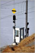Ausfahrsignal in Ospizio Bernina Richtung Bernina Lagalb über dem schneebedeckten Lago Bianco.