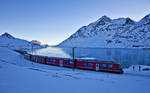 Am frühen Morgen des 28.12.2016 fährt der RhB Triebzug ABe 8/12 3503 mit einem BEX am mit Schwarzeis bedeckten Lago Bianco entlang.