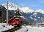 Bernina-Express fährt zwischen Le Prese und Miralago dem Lago di Poschiavo entlang. Hier verläuft ein breiter Weg direkt neben dem Gleis. Le Prese, 19.2.2021