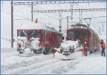 ABe 4/4 II 44 mit Spurpflug und Schleuder kratzt noch den festgepressten Schnee aus Gleis 1 in Ospizio Bernina, whrend Gem 4/4 801 von ihrer Dachlast befreit wird.